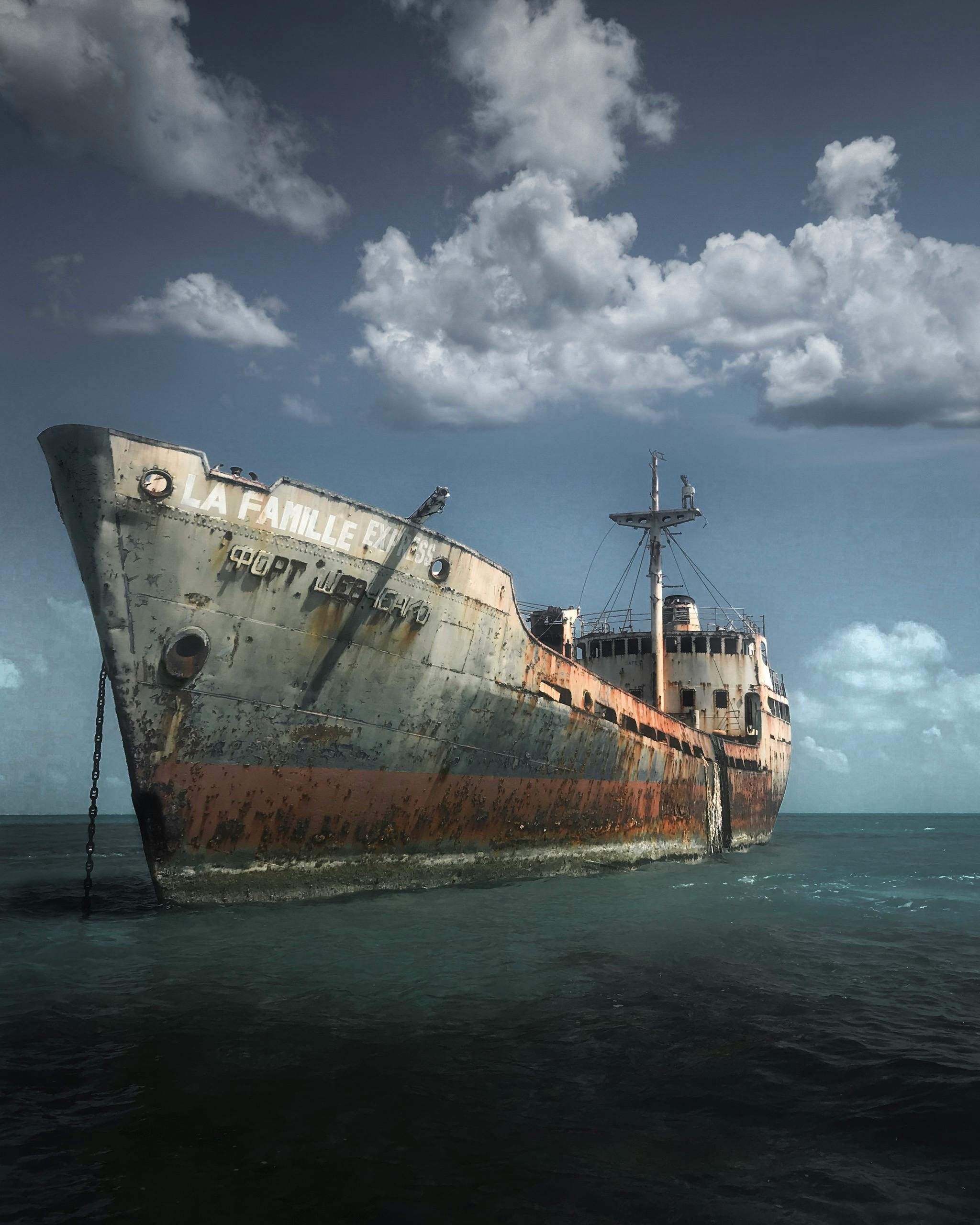 A rusty abandoned ship partially submerged in the ocean under a cloudy sky, evoking nostalgia.